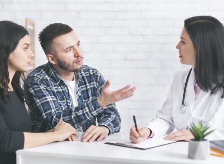 Young childless couple consulting with doctor at clinic