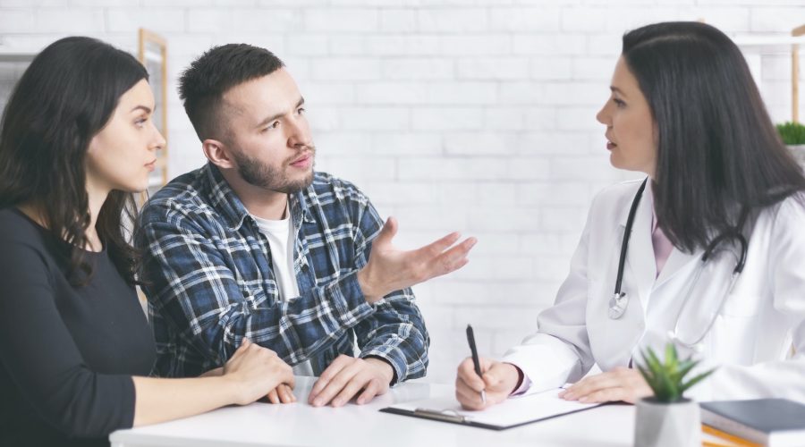 Young childless couple consulting with doctor at clinic