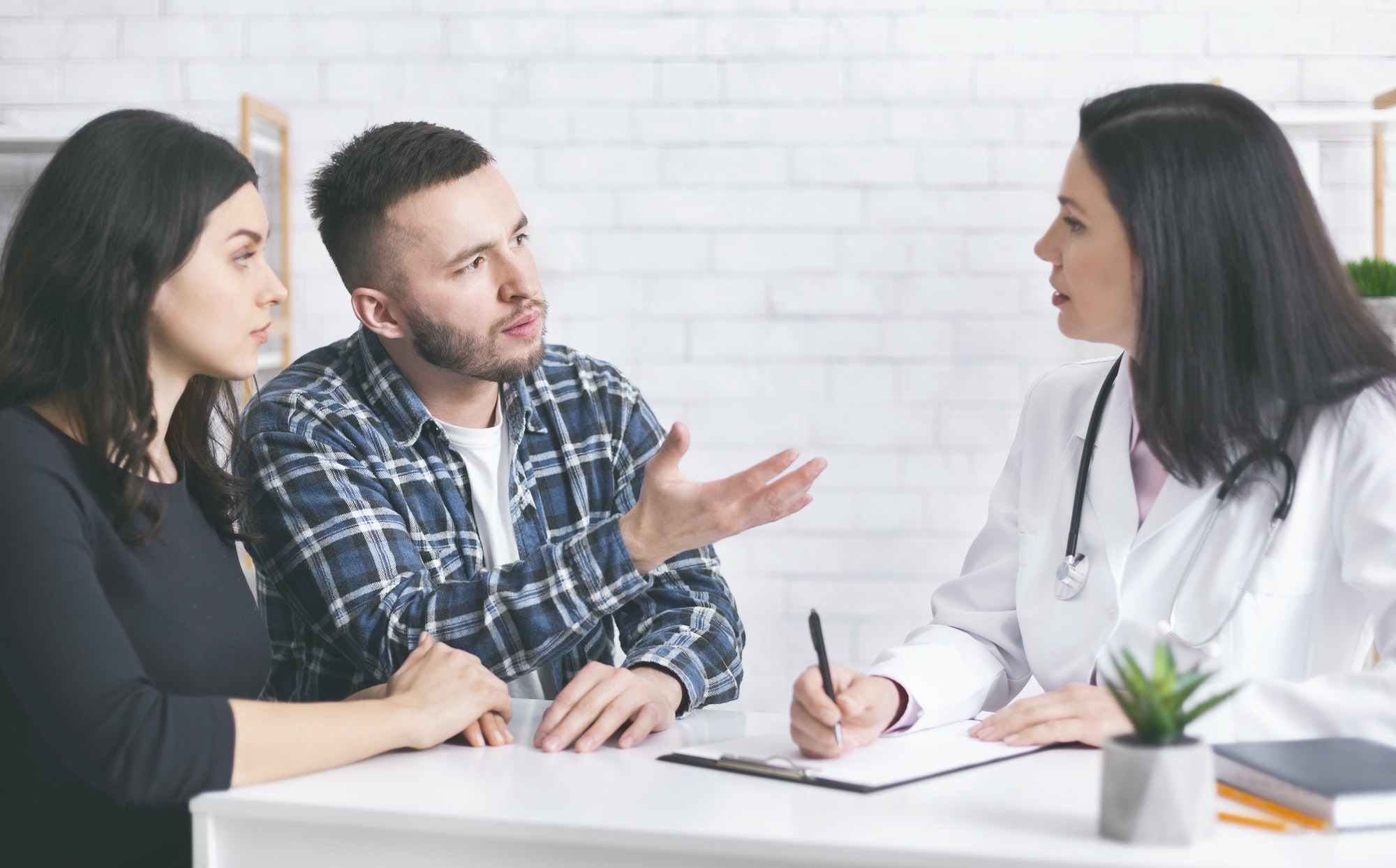 Young childless couple consulting with doctor at clinic